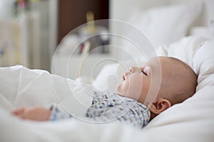 Sick child boy lying in bed with a fever, resting at home