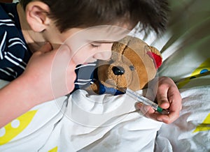 Sick child in bed with teddy bear