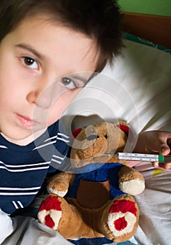 Sick child in bed with teddy bear