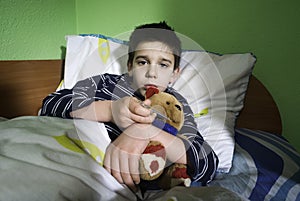 Sick child in bed with teddy bear