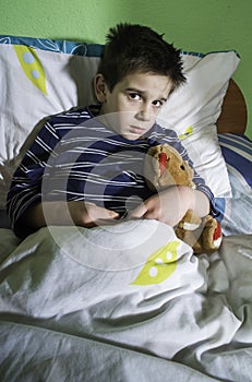 Sick child in bed with teddy bear