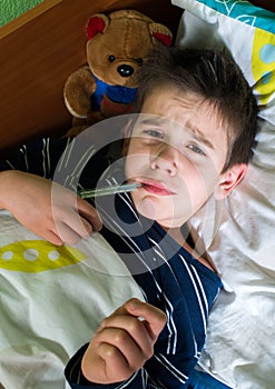 Sick child in bed with teddy bear