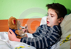 Sick child in bed with teddy bear