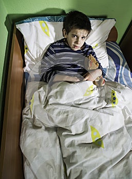 Sick child in bed with teddy bear