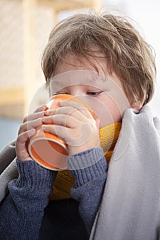 Sick child boy drinking hot tea to recover from flu. sitting in bed a at home