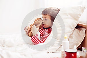 Sick child boy lying in bed with a fever, resting