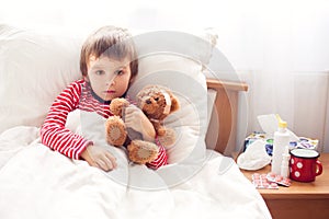 Sick child boy lying in bed with a fever, resting