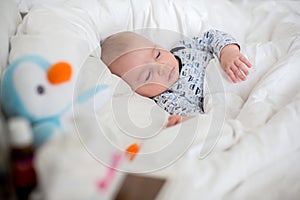 Sick child boy lying in bed with a fever, resting at home