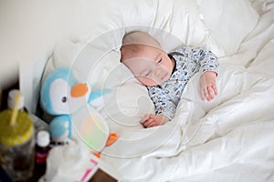 Sick child boy lying in bed with a fever, resting at home