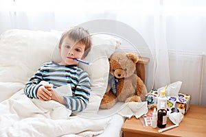 Sick child boy lying in bed with a fever, resting photo