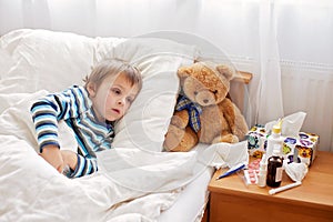 Sick child boy lying in bed with a fever, resting