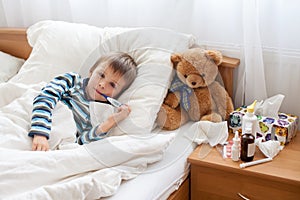 Sick child boy lying in bed with a fever, resting