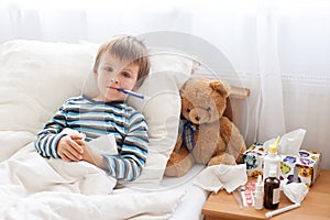 Sick child boy lying in bed with a fever, resting