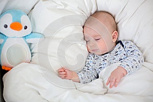 Sick child boy lying in bed with a fever, resting at home