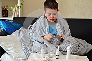 Sick child boy lying in bed with a fever, resting at home. a boy with a cold, treated. medicines, throat nose spray