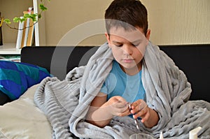 Sick child boy lying in bed with a fever, resting at home. a boy with a cold, treated. medicines, throat nose spray