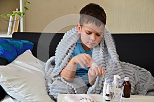 Sick child boy lying in bed with a fever, resting at home. a boy with a cold, treated. medicines, throat nose spray