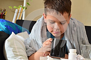 Sick child boy lying in bed with a fever, resting at home. a boy with a cold, treated. medicines, throat nose spray