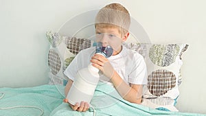 a sick child boy treats his throat with an inhaler at home in bed