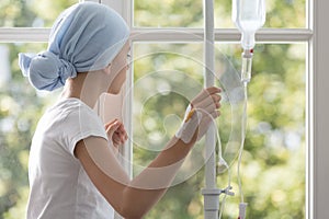 Sick child with drip wearing blue headscarf in the hospital