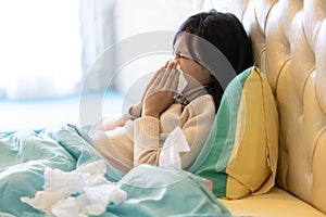 Sick child girl have a cold,blowing nose in paper handkerchief in bedroom,flu or the weather is changing,asian female teenage