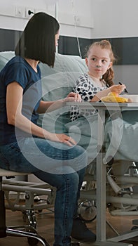 Sick child patient sitting in bed with oxygen nasal tube eating healthy food during lunch