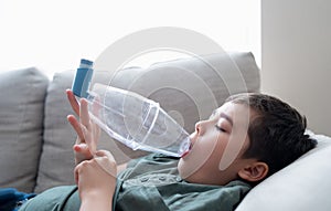 Sick child using asthma inhaler for allergies,Poor boy tired from chest coughing holding inhaler spacer,Tried Kid having asthma