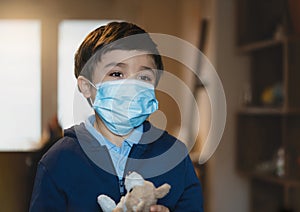 Sick child wearing a protective mask, ill kid in medical face mask standing in living room with sad face,Upset boy standing alone