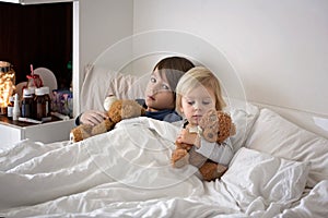 Sick children, boy brothers, lying in bed with a fever, resting