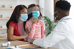 Sick daughter and mother in face masks visiting doctor
