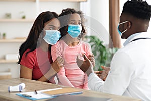 Sick daughter and mother in face masks visiting pediatrician