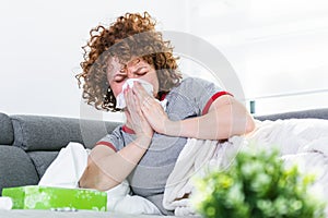 Sick day at home. Young woman has runny and common cold. Cough. Closeup Of Beautiful Young Woman Caught Cold Or Flu Illness.