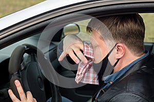 A sick driver in the car wipes his snot with