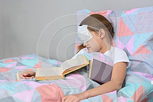 The sick girl fell asleep lying in bed and pulled the mask over her face