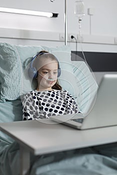 Sick girl with headphones watching funny cartoons on laptop