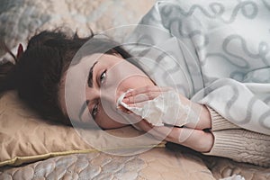 A sick girl lying in bed brought a handkerchief to her nose