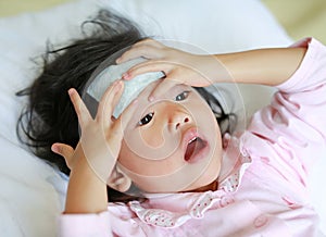 Sick girl lying on the bed with a cool jell in the face