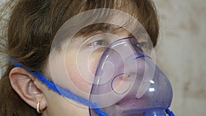 A sick girl in a mask inhales a spray bottle. Woman in a blue hospital mask. Inhale vapors from the respiratory tract