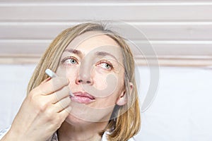 Sick girl measures temperature with thermometer in her mouth on light background. Concept diseases of flu virus, colds,