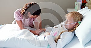 Sick girl in oxygen mask resting on bed