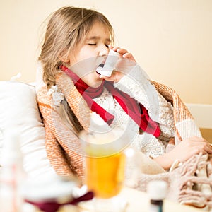 Sick girl with respiratory illness lying in bed and using inhale