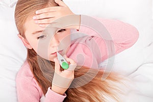 Sick girl resting in bed with fever meassuring temperature with photo