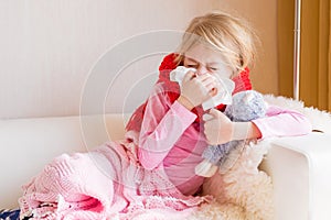 Sick girl with runny nose sitting in sofa photo