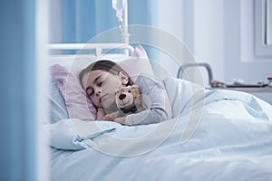 Sick girl sleeping with teddy bear in the hospital