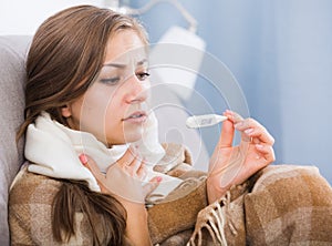 Sick girl on sofa with thermometer