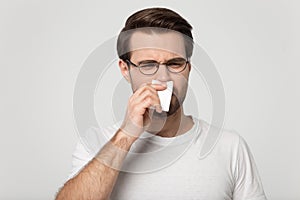 Sick guy sneezing wiping nose or suffers from unpleasant smell