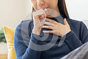 Sick, hurt or pain asian young woman, girl with sore throat, cough have a fever, flu and sneezing nose, runny sitting on sofa bed