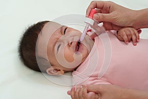 sick infant baby crying while refuses eating liquid medicine with dropper