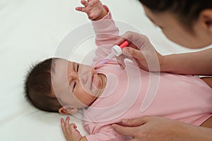 sick infant baby crying while refuses eating liquid medicine with dropper