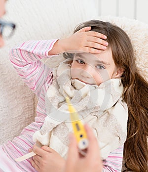 Sick kid with high fever laying in bed and mother taking temperature